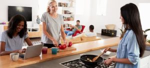 group of friends cooking, working and socialising in open plan kitchen