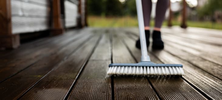man sweeping decking with brush