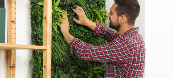 Man installing green artificial plant panel