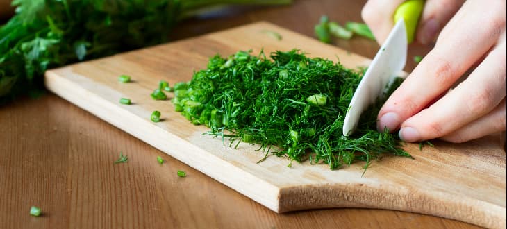 person cutting vegetables on chopping board