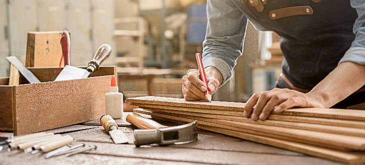 man measuring timber in workshop