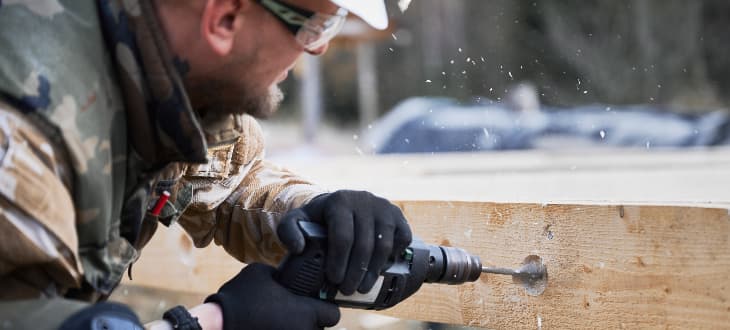 man drilling decking in winter
