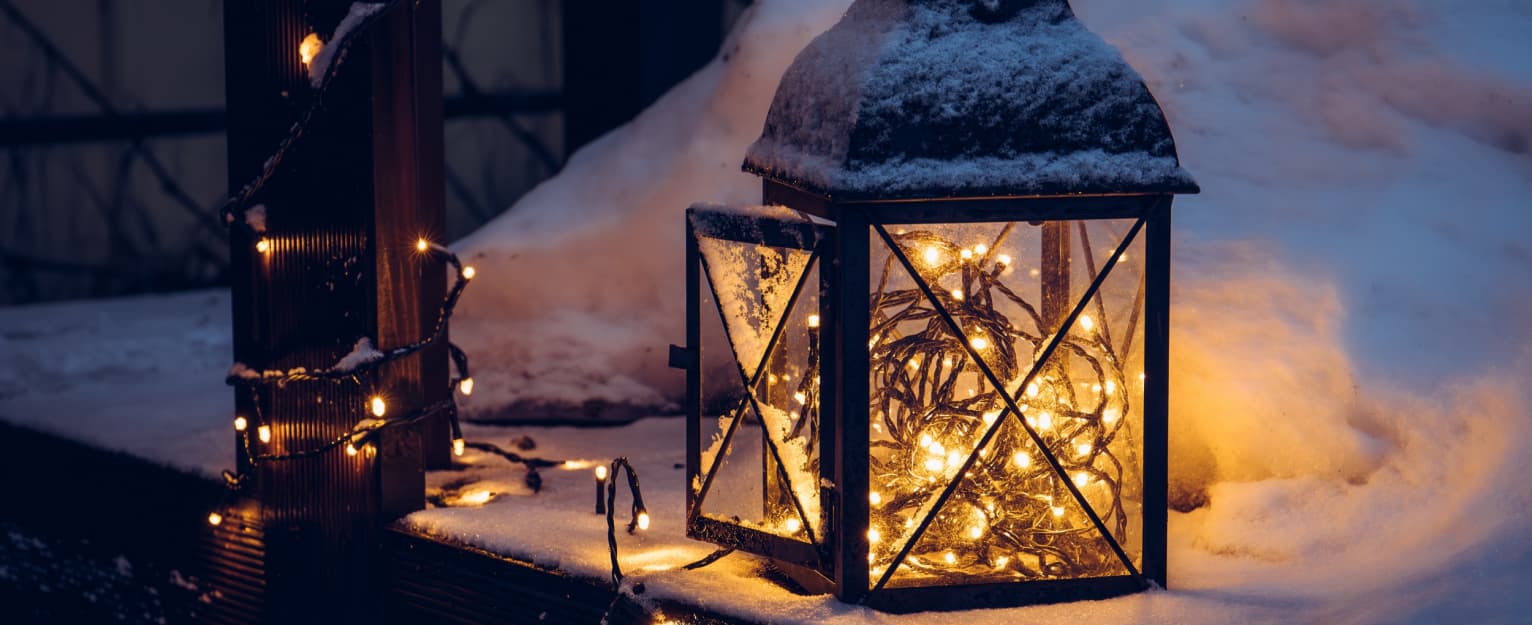 lantern with fairy lights on snowy decking