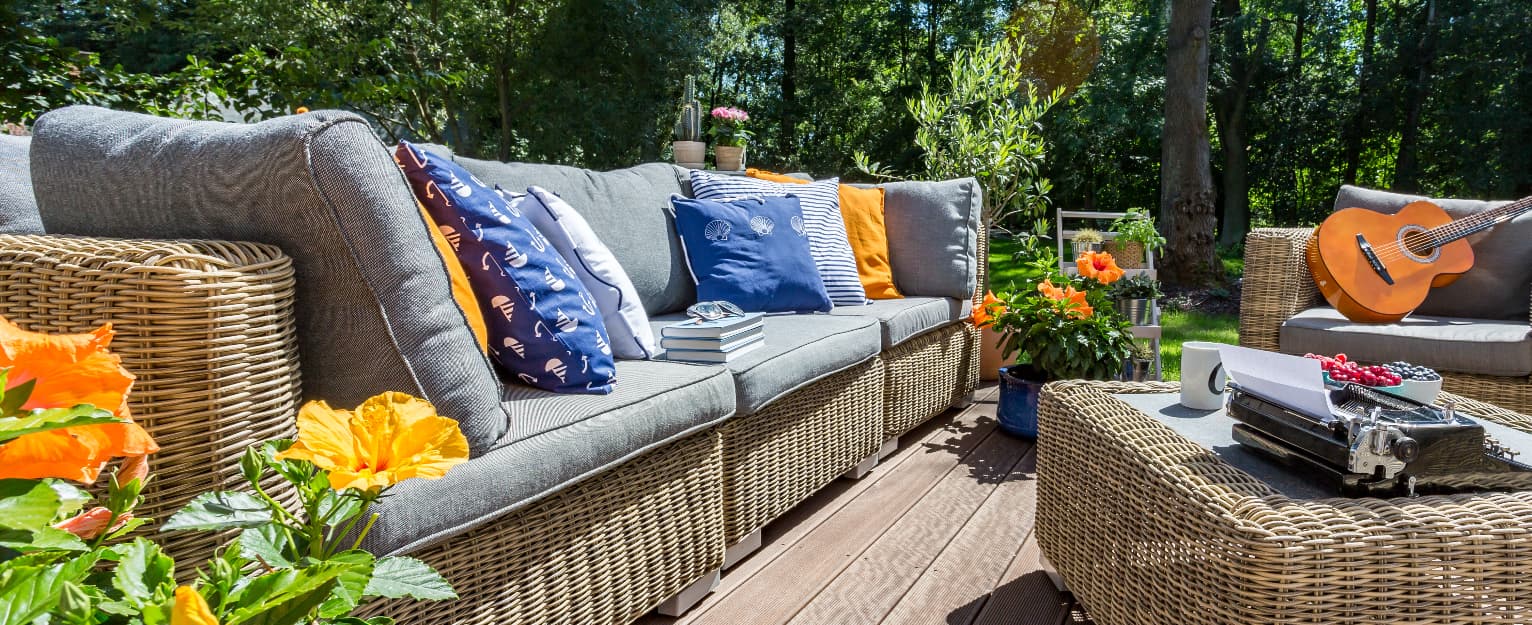 cosy garden decking with furniture cushions, a guitar and decorated with plants