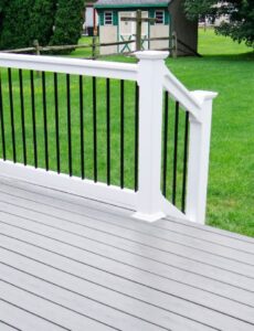 Grey composite decking with white and black balustrade railing overlooking a landscaped garden area