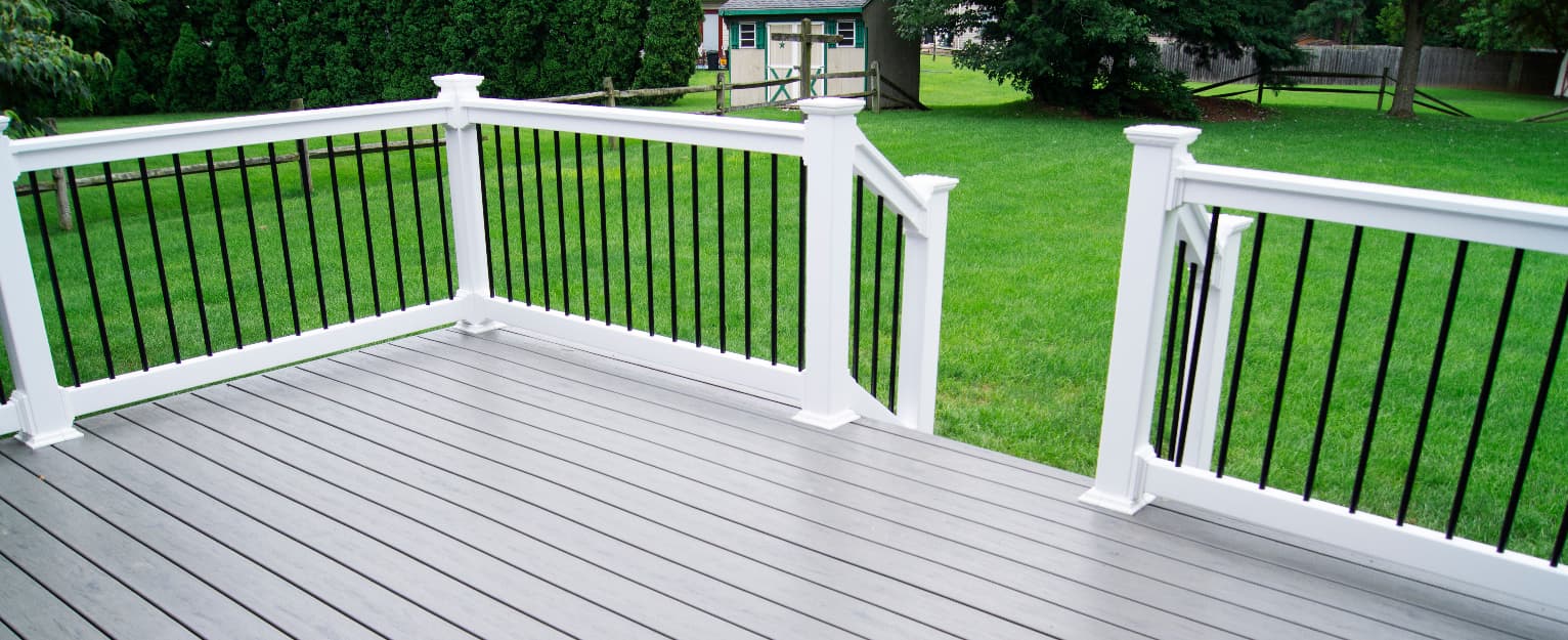Grey composite decking with white and black balustrade railing overlooking a landscaped garden area