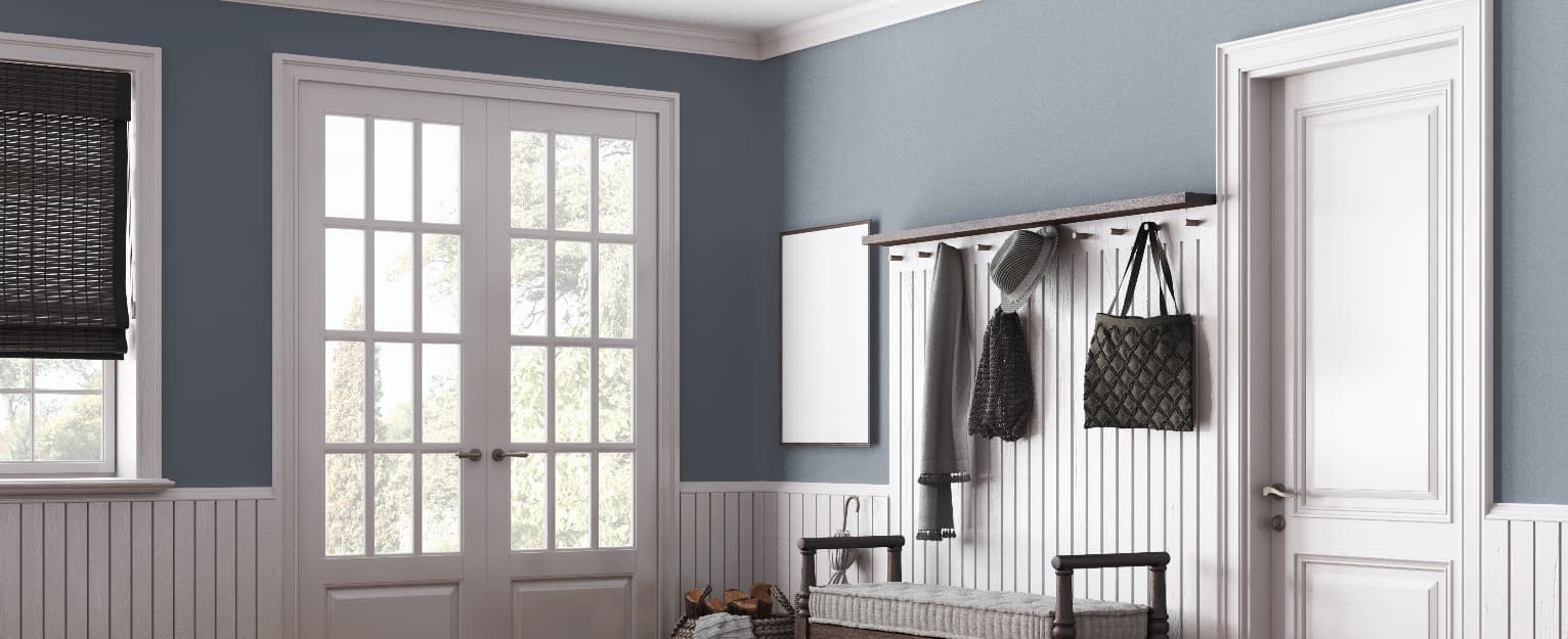 White internal doors in a modern hallway with blue walls, glazed French doors, and decorative wall panelling