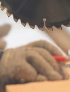 Close-up of a tradesperson cutting timber with a circular saw in a workshop, demonstrating precision woodworking and timber preparation for construction or DIY projects.